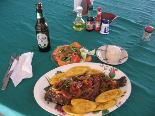 einen Tisch mit einem Teller Essen und einer Flasche Bier in der Unterkunft Finca Joco Mico in Diriamba