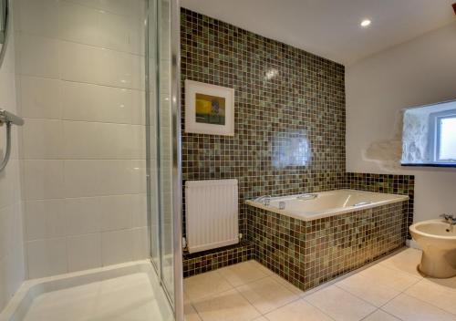 a bathroom with a shower and a tub and a toilet at The Corn Mill in Solva