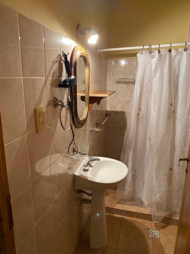 y baño con lavabo, espejo y ducha. en Departamentos Ailen en Esquel