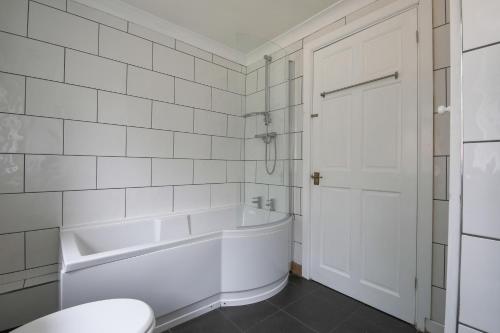 a white bathroom with a tub and a toilet at A Perfect 3BD Home away from Home Canton Cardiff in Cardiff