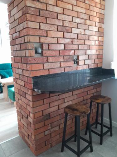 a brick wall with a bar and two stools at Apartament Królewiecka 54b/26 in Mrągowo