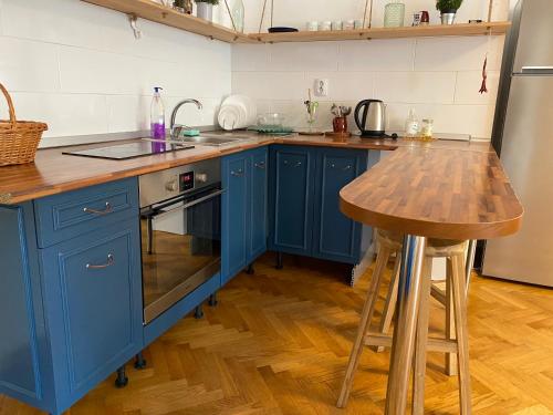 une cuisine avec des placards bleus et une table en bois dans l'établissement Stylized and modern apartment in Bucharest, à Bucarest