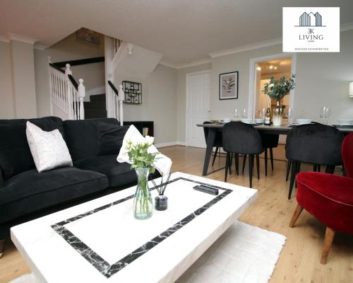 a living room with a black couch and a table at Spacious 3 Bedroom Duplex Apartment On Cardiff Bay - Free Private Parking - By EKLIVING LUXE in Cardiff