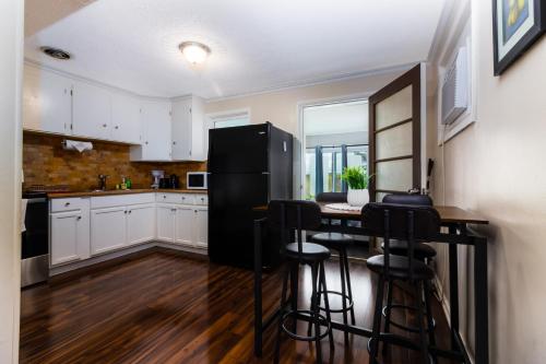 een keuken met een zwarte koelkast en een tafel met krukken bij The Gorge View Villa- With Private Yard & Free Parking-see full listing info in Niagara Falls