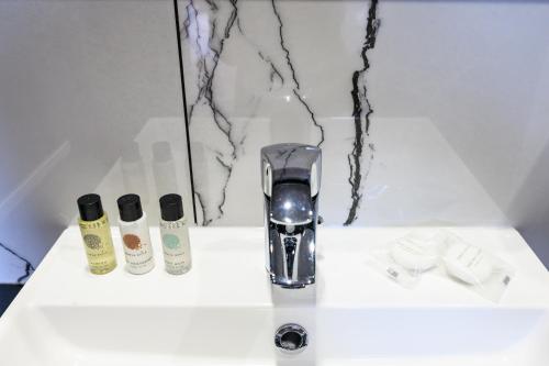 a sink with a blow dryer and two bottles of soap at Hôtel D'Alsace in Paris