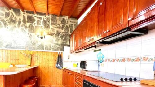 kuchnia z drewnianymi szafkami i kamienną ścianą w obiekcie Casa Rural Ondina w mieście Hermigua