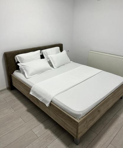 ein Bett mit weißen Laken und Kissen in der Unterkunft The Bliss in Râmnicu Vâlcea