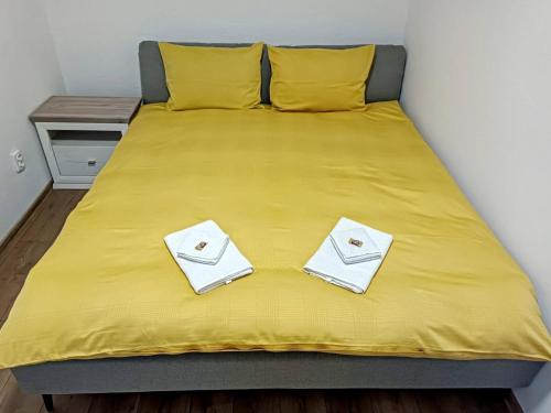 a large yellow bed with two white towels on it at Lend City Apartment in Miercurea-Ciuc