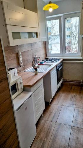a kitchen with white appliances and a wooden floor at Lend City Apartment in Miercurea-Ciuc
