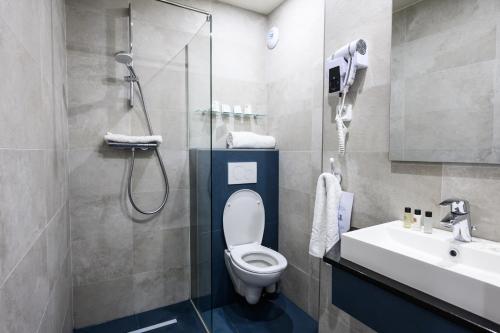 La salle de bains est pourvue d'une douche, de toilettes et d'un lavabo. dans l'établissement Hôtel D'Alsace, à Paris