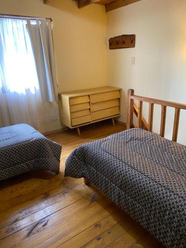 a bedroom with two beds and a dresser and a window at Departamentos Ailen in Esquel