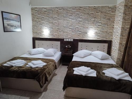 two beds in a hotel room with towels on them at Hotel Villa Pigasos in Paralia Katerinis