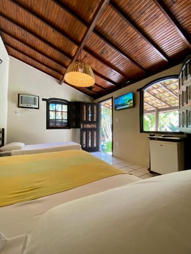 a bedroom with a large yellow bed in a room with windows at Pousada Tubarão in Arraial d'Ajuda