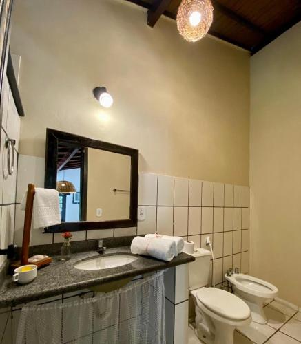 a bathroom with a toilet and a sink and a mirror at Pousada Tubarão in Arraial d'Ajuda