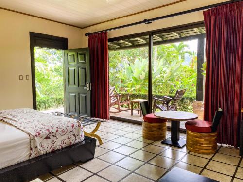 a bedroom with a bed and a patio with a table and chairs at Arenal Manoa Resort & Hot Springs in Fortuna