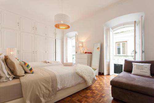 a white bedroom with a bed and a couch at Ginjinha House - 4 Rooms - Bairro Alto - with AC by Lisbeyond in Lisbon
