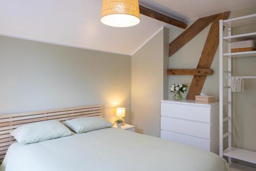 a bedroom with a white bed and a book shelf at Gîte Le Haut des Vannes in Neufchâteau