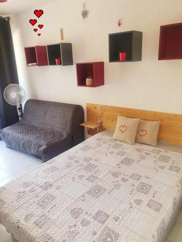 une chambre avec un lit et un canapé et des cœurs sur le mur dans l'établissement coquet Studio Classé Deux Étoiles, Balcon avec Table, et Wifi, à Gréoux-les-Bains