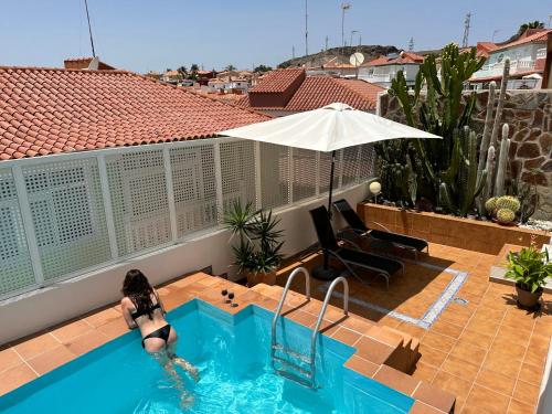 a woman is in a swimming pool with an umbrella at BellaVista DM private pool in San Bartolomé