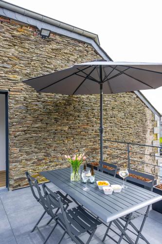 a table with an umbrella on a patio at Gîte Le Haut des Vannes in Neufchâteau