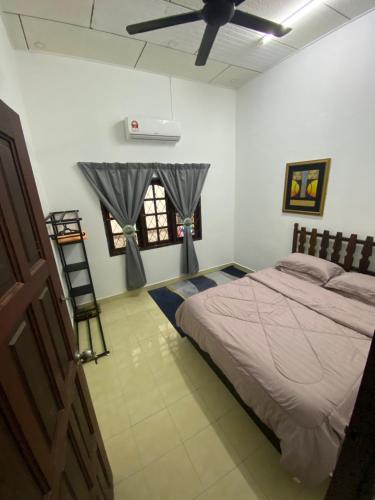 sypialnia z łóżkiem i wentylatorem sufitowym w obiekcie Simple1 Guesthouse w mieście Pantai Cenang