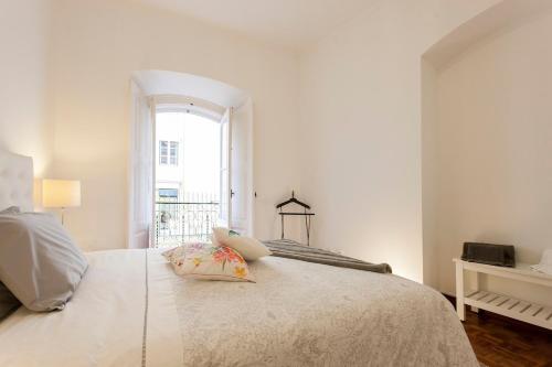 1 dormitorio blanco con 1 cama grande y ventana en Ginjinha House - 4 Rooms - Bairro Alto - with AC!, en Lisboa