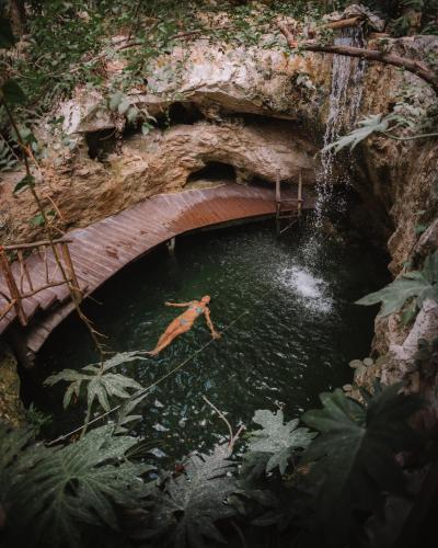 a person jumping into a pool of water under a bridge at Kan Tulum Hotel in Tulum