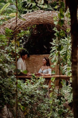 a man and woman sitting at a table in a garden at Kan Tulum Hotel in Tulum
