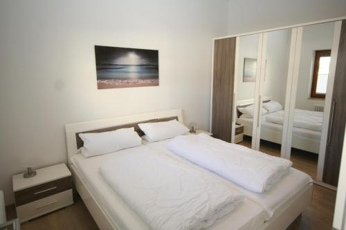 una camera con letto bianco e specchio di Haus Belvedere App 12 WLAN inkl a Grömitz