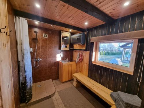ein Bad mit einer Dusche, einer Bank und einem Fenster in der Unterkunft Gatiņi in Ventspils