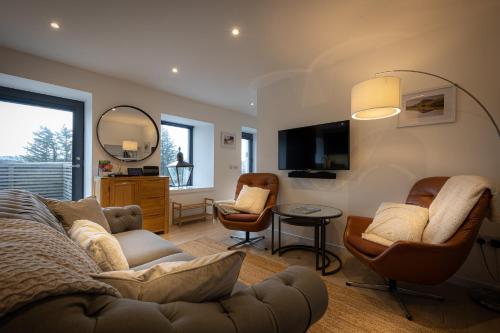 un soggiorno con divano, sedie e TV di Tidal Cottage ad Ardvasar