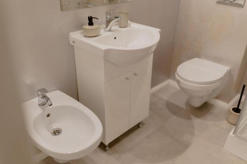 a white bathroom with a toilet and a sink at No. 55 in Buzau