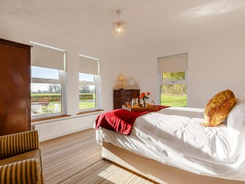 a bedroom with a large bed and two windows at Highgrove in Gissing