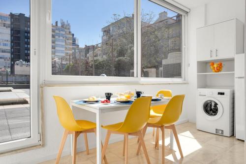 a dining room with a white table and yellow chairs at Sunny Suites Lisbon in Lisbon