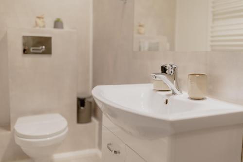 a white bathroom with a toilet and a sink at No. 55 in Buzau