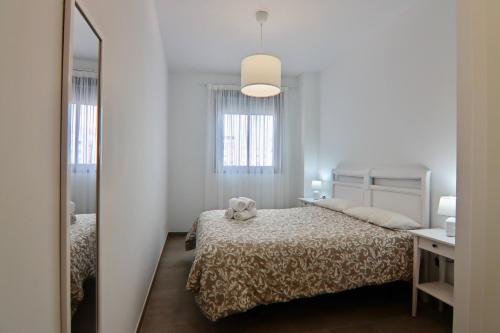ein weißes Schlafzimmer mit einem Bett und einem Spiegel in der Unterkunft Apartamento San Leonardo Playa (Free Parking) in Cádiz