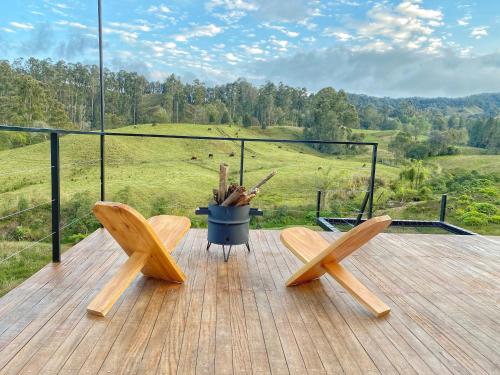 two wooden chairs on a deck with a view of a field at Bohemia Glamping in La Unión