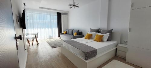 a white bedroom with a bed and a chair at Aqua Magic Lake On Luminita Studio in Mamaia