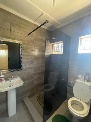 a bathroom with a shower and a toilet and a sink at Reed Mat Lodge, Furnished Stand-alone 4 bedroomed house in Lusaka
