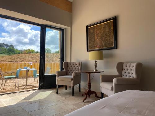 une chambre avec un lit, deux chaises et une table dans l'établissement Le Bos Dordogne, à Soulaures