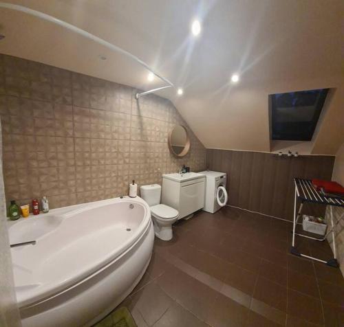 La salle de bains est pourvue d'une baignoire blanche et de toilettes. dans l'établissement 3 BD Spacy Centrum apartment 110m2, à Kaunas