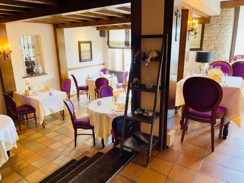 a restaurant with white tables and purple chairs at Hostellerie Sainte-Cécile in Florenville