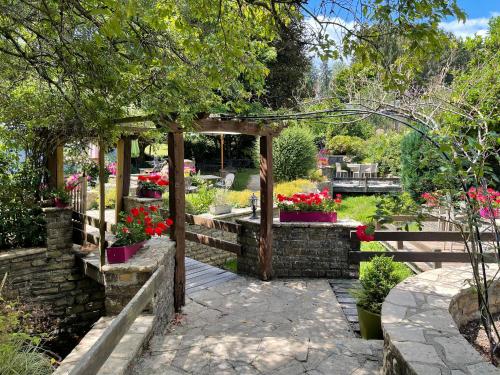 a garden with a wooden pergola and flowers at Hostellerie Sainte-Cécile in Florenville