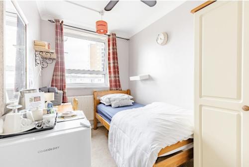 małą sypialnię z łóżkiem i umywalką w obiekcie Exclusive rooms w Londynie