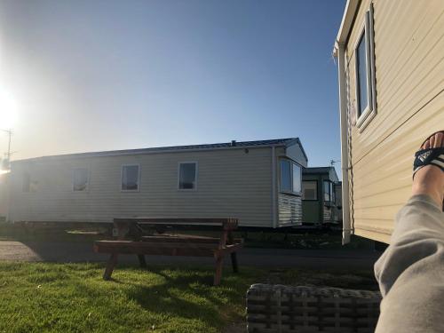 a person with their feet up on a bench next to a house at 2 Bedroom 6 berth Caravan Towyn Rhyl in Rhyl