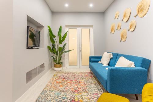 ein Wohnzimmer mit einem blauen Sofa und einem Teppich in der Unterkunft Wonderful Brand New Apartment Belém - A few steps away from the River! in Lissabon