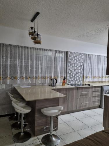 a kitchen with a counter and stools in it at Stella Maris 104 Amanzimtoti in Amanzimtoti