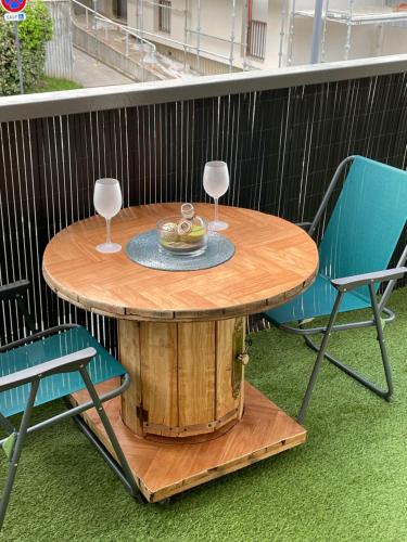 a wooden table with two wine glasses and two chairs at Bel appartement composé de deux chambres in Saint Etienne