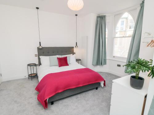 Un dormitorio con una cama grande con una manta roja. en The Salthouse Apartment 1, en Scarborough