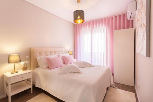Un dormitorio con una cama blanca y cortinas rosas. en Urban Views - ML inspired by Torre dos Clérigos, en Oporto